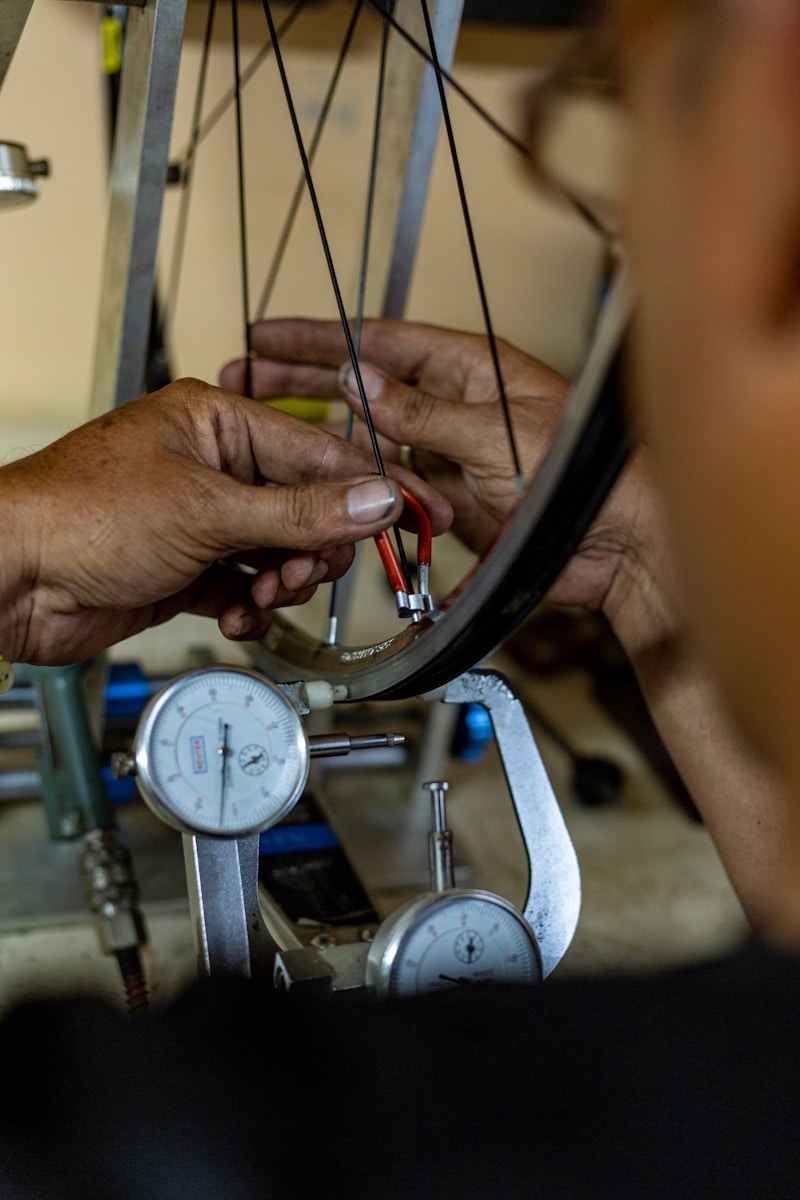 Mechanic adjusting bicycle wheel spokes with tools.